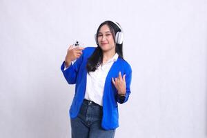 beautiful adult office woman wearing blue formal suit standing smiling to camera while carrying smartphone and headphone while dancing isolated white background. for technology, music, entertainment photo