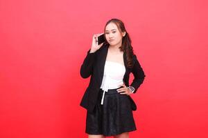 expression of a young asian career woman pouting at the camera wearing a black formal suit while calling someone on a smartphone, for technology, business, advertising, financial content photo