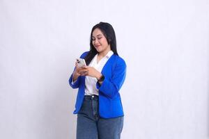 beautiful young office woman wearing blue formal suit standing on right side wide smile candid both hands playing with cellphone. for technology content, lifestyle, mobile transactions photo