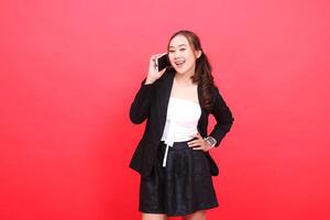 expression of a young asian career girl laughing at the camera wearing a black formal suit while calling people via smartphone, for technology, business, advertising, financial content photo