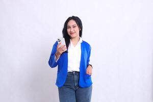 The charm of a beautiful young office woman wearing a blue formal suit standing smiling at the camera operating a smartphone while putting it in her suit pocket. for technology, mobile transactions photo