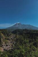Panorama of Mount Merapi from close range with beautiful views in the summer in the morning. Active volcano landscape in detail with forest and ravine in front photo