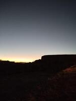 the sun is setting over a hill with a mountain in the background photo