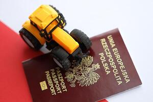 Red polish passport and yellow tractor on smooth red and white flag of Poland photo