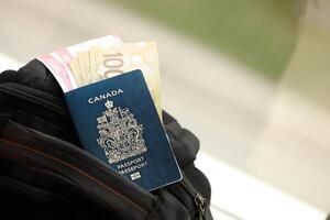 Canadian passport and dollar money bills with airline tickets on backpack photo