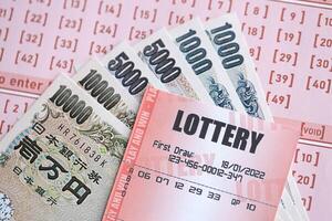Lottery tickets lies with japanese yen bills on gambling sheets with numbers for marking to play lottery photo