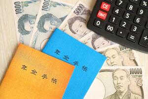 Japanese pension insurance booklets on table with yen money bills and calculator on table photo