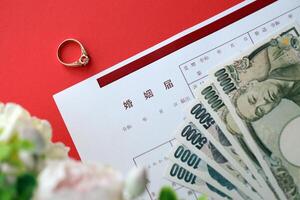 Japanese marriage registration blank document and wedding proposition ring and yen money on table photo