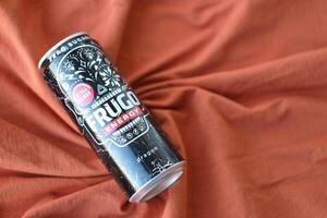 KYIV, UKRAINE - APRIL 20, 2024 Frugo energy drink in black can on orange fabric. Frugo is now owned by Food Care Poland photo
