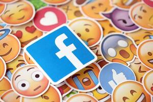 KYIV, UKRAINE - APRIL 20, 2024 Facebook logo and large set of stickers with Emoji yellow faces. Emoji is a pictogram or smiley embedded in text and used in electronic messages photo