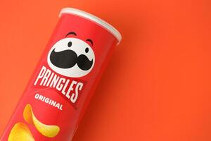 KYIV, UKRAINE - APRIL 20, 2024 Pringles original potato chips on red background. Pringles is a brand of potato snack chips photo