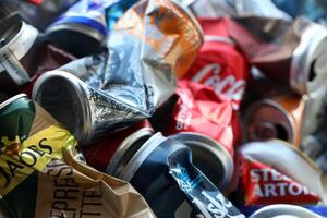 KYIV, UKRAINE - APRIL 20, 2024 Background of various crashed beer cans. Recycle aluminum metal crushed tin can waste photo