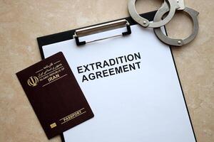 Passport of Iran and Extradition Agreement with handcuffs on table photo