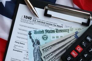 United States 1040 tax form individual income tax return with refund check and US dollar bills photo