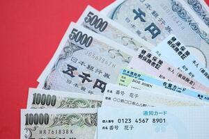 Blue and red Japan Health Insurance cards on table with japanese residence card and my number card photo
