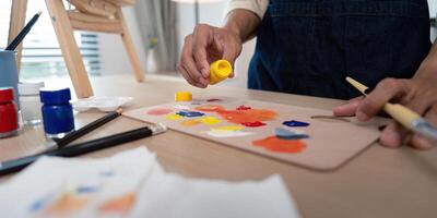 Artist Mixing Paints on Palette in Studio with Brushes and Easel in Background photo