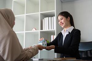 Real Estate Agent Showing Model House to Muslim Customer in Modern Office Setting photo