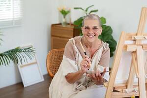 Senior Woman Smiling While Painting on Canvas in Bright, Modern Home Studio with Plants and Natural Light photo