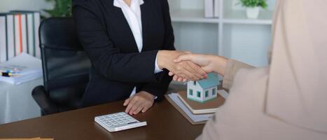 Real Estate Agent Shaking Hands with Muslim Customer in Office Setting, Discussing Property Purchase photo