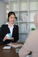 Real Estate Agent Presenting House Model to Muslim Client in Modern Office Setting photo