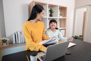 Mother and Child Working from Home Together in Modern Home Office Setting with Laptop and Documents photo