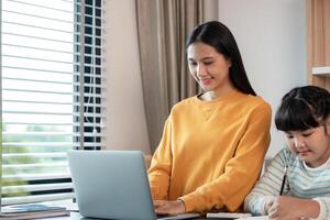 Mother and Child Working from Home Together in a Modern Home Office Setting with Laptop and Study Materials photo