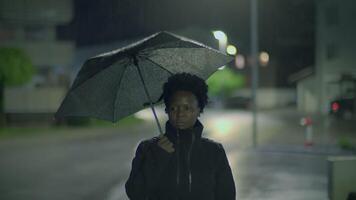 A woman walking alone in the rain at night with an umbrella, creating a calm atmosphere video