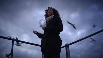 A woman holds a transparent sphere with seagulls flying, creating a dreamy atmosphere video