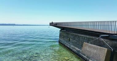 A rustic pier extends over clear coastal waters beneath a blue sky on a calm day, a serene scene video