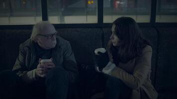 Conversation between two individuals holding coffees at night in an urban setting video
