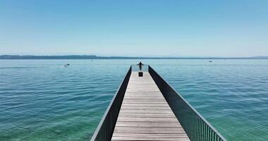 A wooden pier extends into the calm blue sea under a clear sky, offering relaxation and reflection video