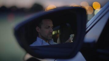 A person is actively using a smartphone while inside their car during dusk hours video