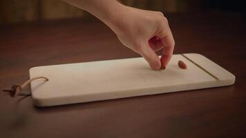 A hand is placing an invisible item on a wooden cutting board on a dark table surface video