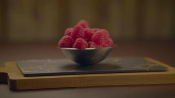 A display of fresh raspberries in a metal bowl placed on a wooden cutting board video