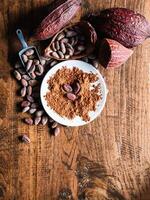 Top view of Natural cocoa powder with brown cocoa beans and dry cacao pod on a vintage wooden table. photo