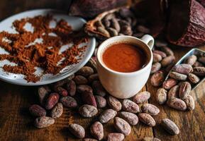 Hot chocolate drink,cocoa drink and natural cocoa powder with brown cocoa beans and dry cacao pod on a vintage wooden table. photo