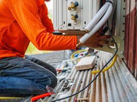 Air conditioning technicians install new compressor air in homes, Repairman fix air conditioning systems, Male technician service for repair and maintenance of air conditioners photo