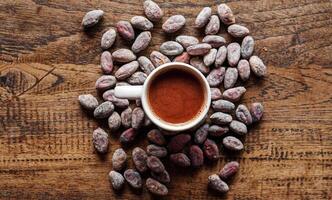 Hot chocolate drink,cocoa drink and natural cocoa powder with brown cocoa beans on a vintage wooden table.Top view photo