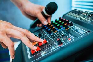 Close-up of sound engineer hands adjusting control sound mixer in recording, broadcasting studio,Sound mixer. Professional audio mixing console, buttons, faders and sliders. sound check. photo