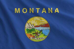 Montana US state flag depicted on folded wavy fabric of old cloth photo
