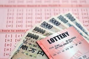 Lottery tickets lies with japanese yen bills on gambling sheets with numbers for marking to play lottery photo