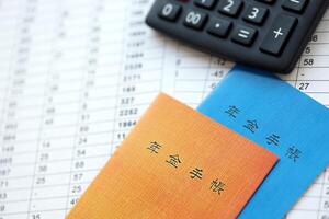 Japanese pension insurance booklets on table with calculator on table photo
