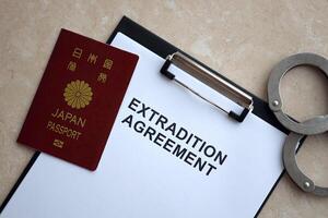 Passport of Japan and Extradition Agreement with handcuffs on table photo