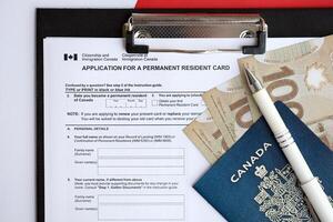 Application for permanent resident card on table with pen and canadian passport with money photo