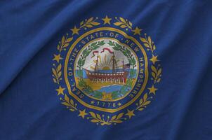New Hampshire US state flag depicted on folded wavy fabric of old cloth photo