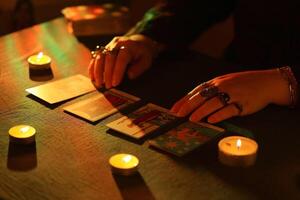 KYIV, UKRAINE - JULY 10, 2024 Tarot reader picking tarot cards. Candlelight in dark room. Tarot reader or fortune teller reading and forecasting photo