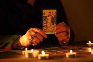 KYIV, UKRAINE - JULY 10, 2024 Tarot reader picking tarot cards. Candlelight in dark room. Tarot reader or fortune teller reading and forecasting photo
