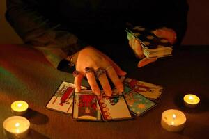 KYIV, UKRAINE - JULY 10, 2024 Tarot reader picking tarot cards. Candlelight in dark room. Tarot reader or fortune teller reading and forecasting photo