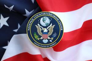 KYIV, UKRAINE - JUNE 26, 2024 United States National Counterterrorism Center coat of arms sticker on folded US flag photo