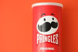 KYIV, UKRAINE - APRIL 20, 2024 Pringles original potato chips on red background. Pringles is a brand of potato snack chips photo